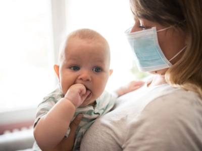 Mamma con mascherina e neonato in braccio