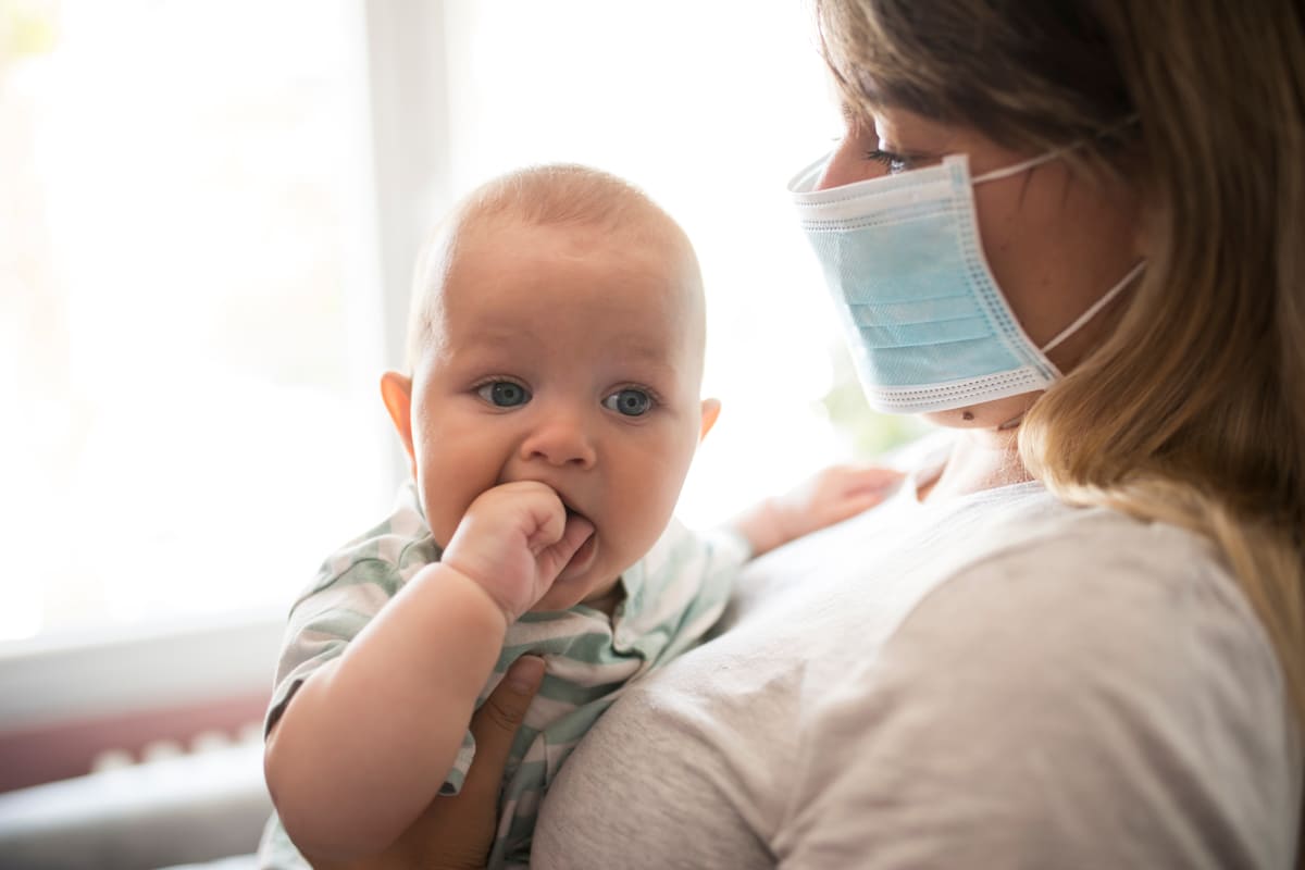 Mamma con mascherina e neonato in braccio