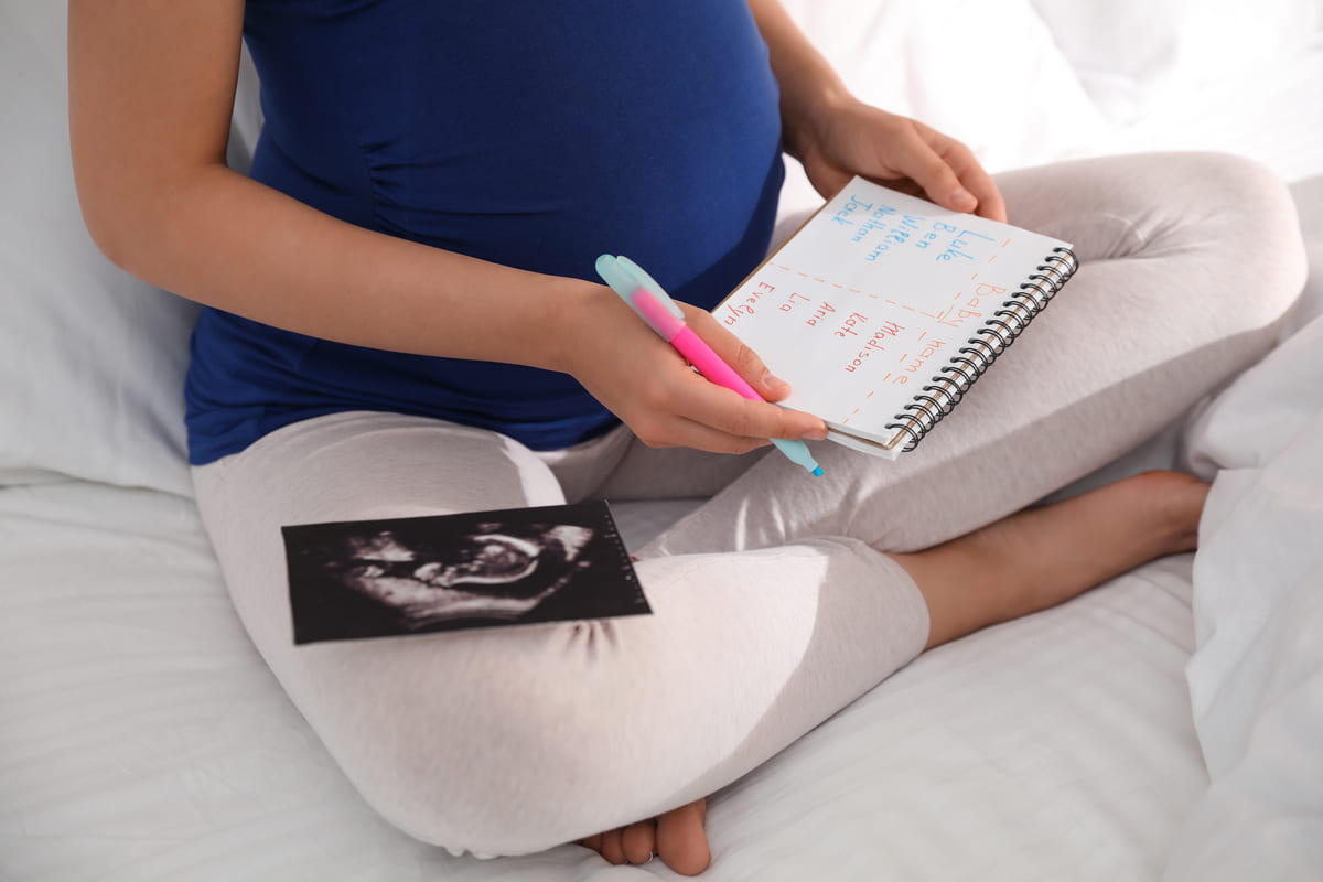 Donna incinta con lista di nomi di bambini