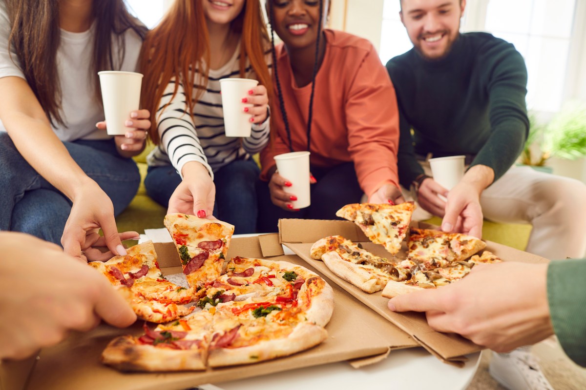 Amici che fanno cena insieme a casa con la pizza