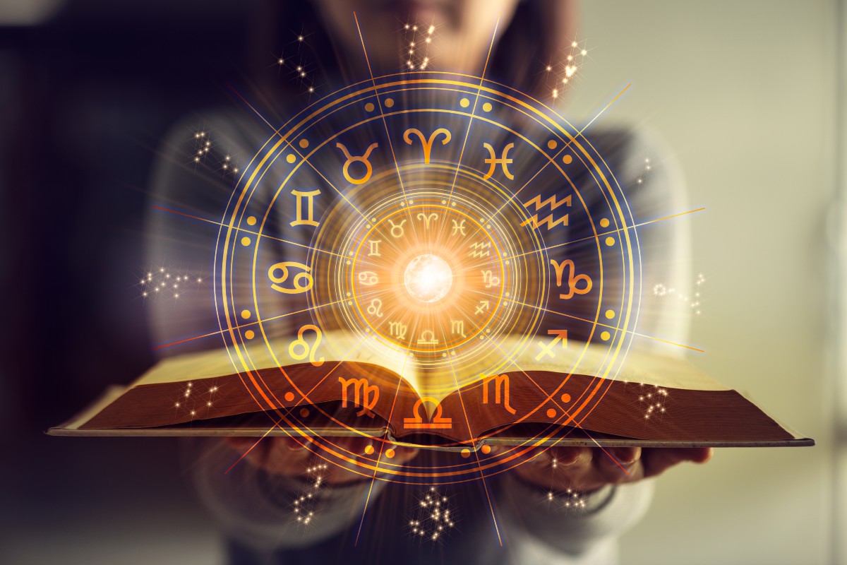 Una persona tiene aperto un libro sull’astrologia