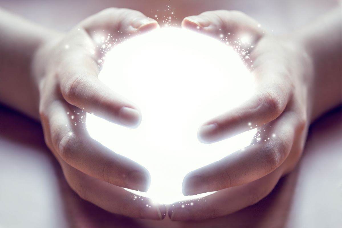 Mani reggono una palla luminosa