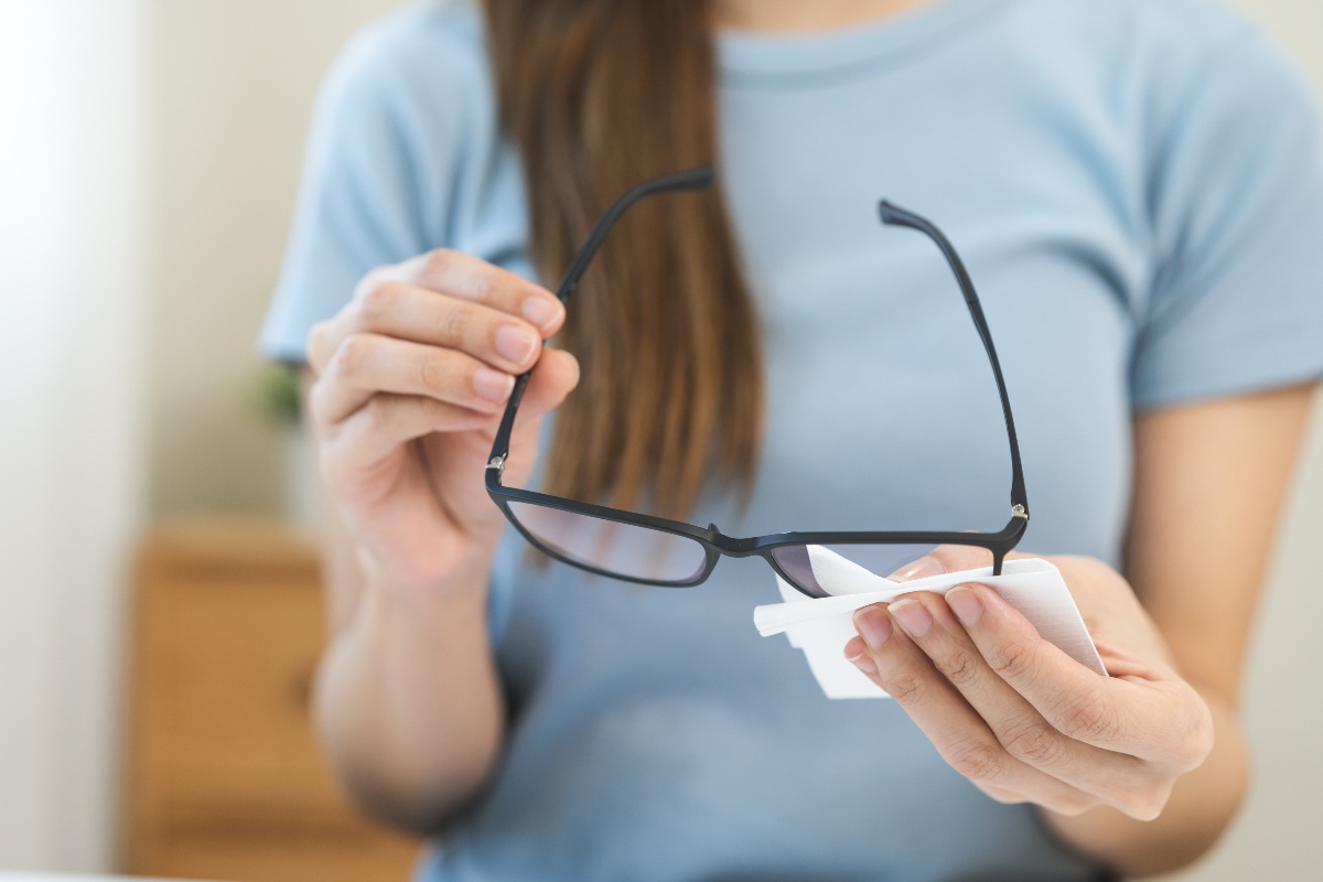 Una donna pulisce gli occhiali con un panno